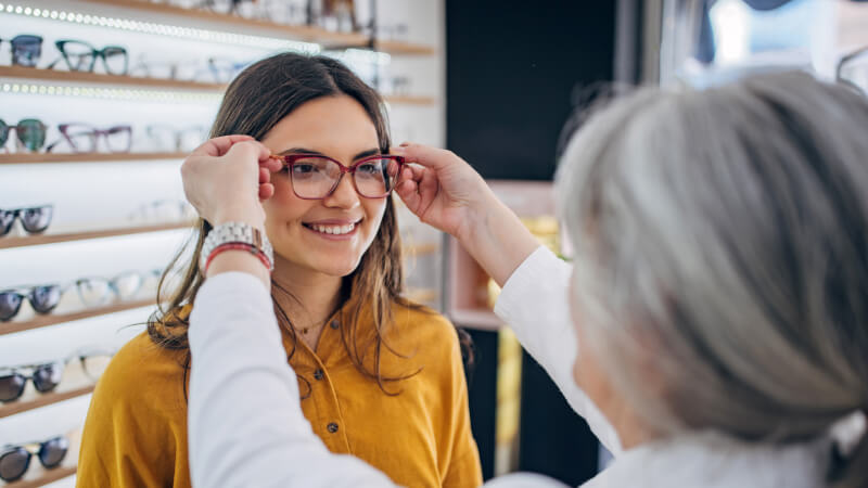 Profesional de óptica ajustando unas gafas a una clienta